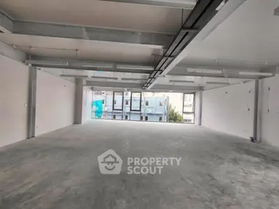 Spacious open-plan commercial space with large windows and industrial ceiling design.