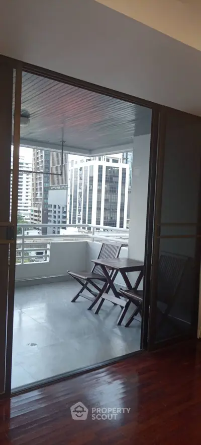 Spacious balcony with city view and wooden furniture in modern apartment