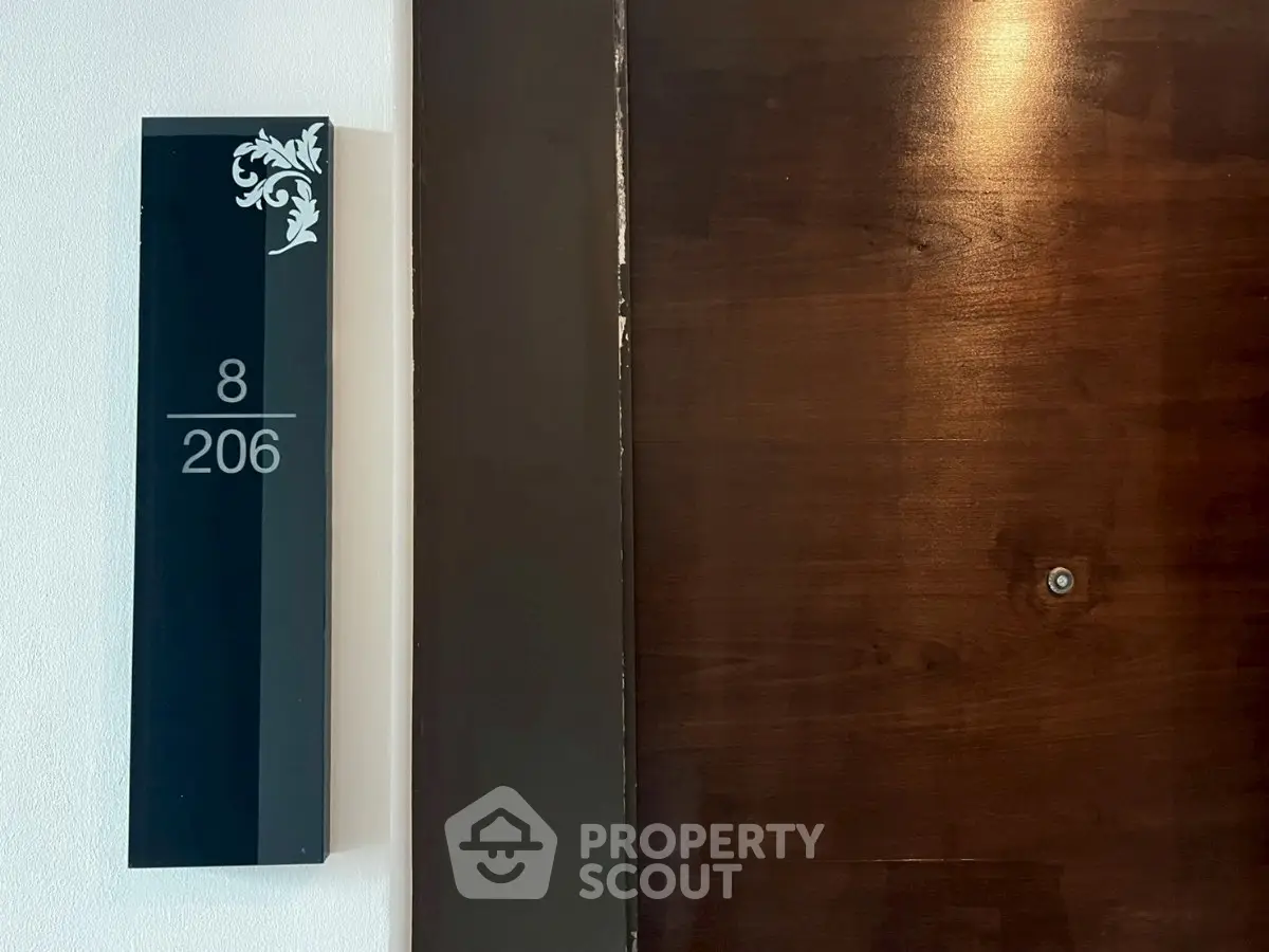 Elegant apartment entrance with stylish door and room number plaque, showcasing modern design.