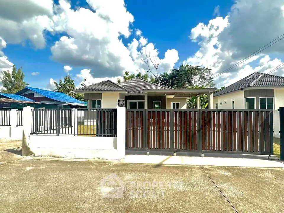 Charming single-story home with modern fence and lush greenery under a bright blue sky.