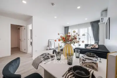 Modern living room with stylish dining area and cozy seating, featuring elegant decor and ample natural light.