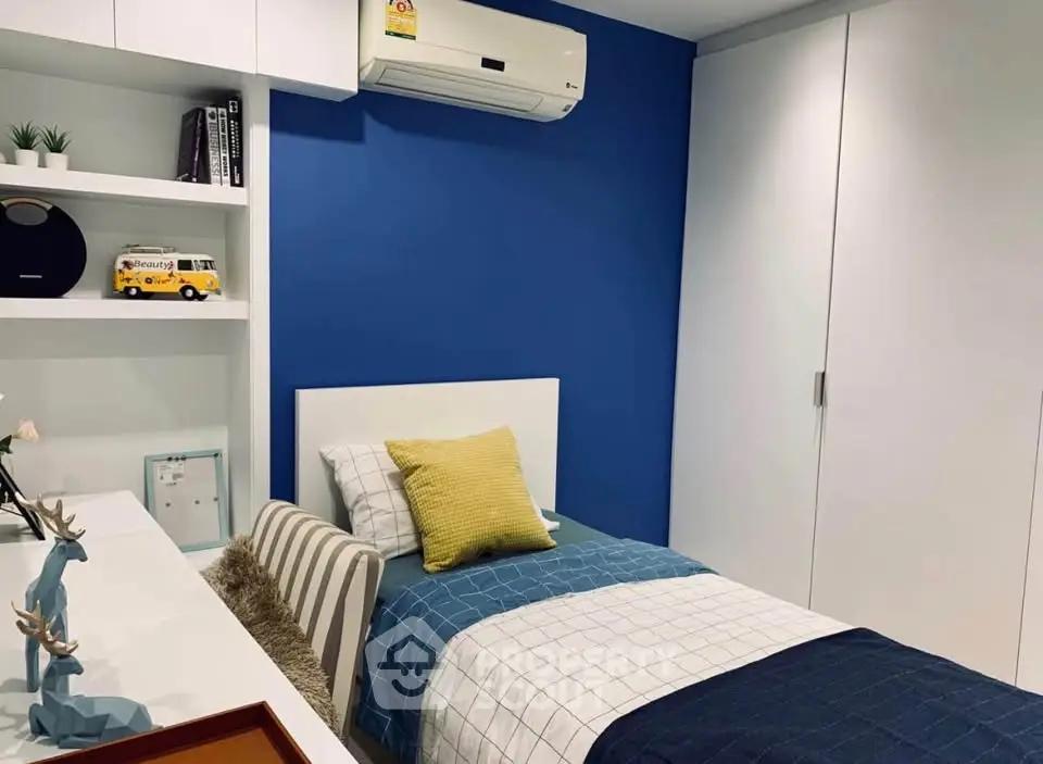 Modern bedroom with blue accent wall, sleek white furniture, and cozy single bed.