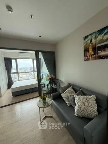 Modern living room with a view into a stylish bedroom, featuring elegant decor and a cityscape painting.