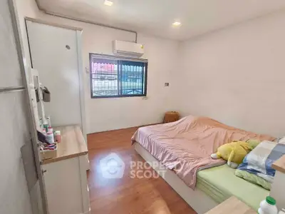 Cozy bedroom with wooden flooring and natural light, featuring a comfortable bed and air conditioning.