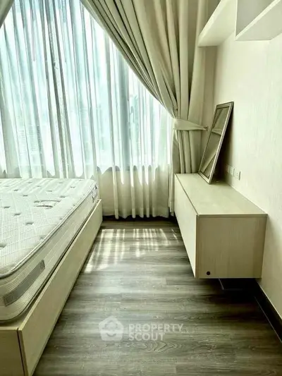 Bright bedroom with large window and modern furnishings, featuring a comfortable bed and sleek flooring.