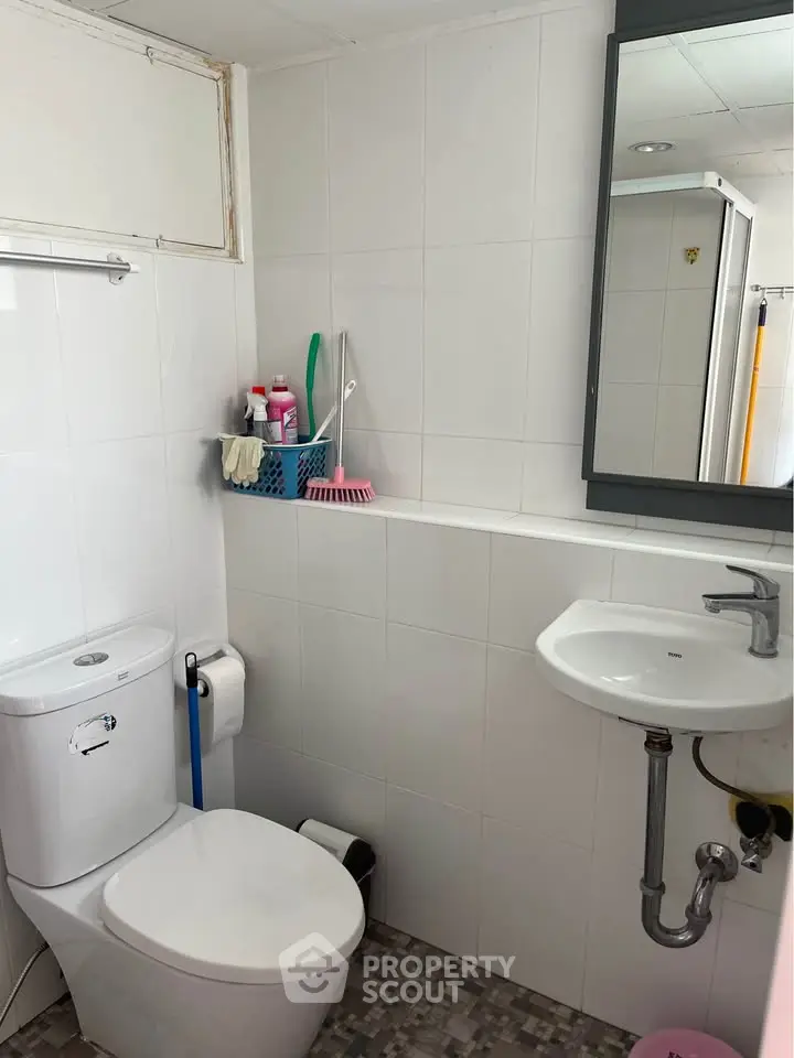 Compact modern bathroom with white tiles and essential fixtures
