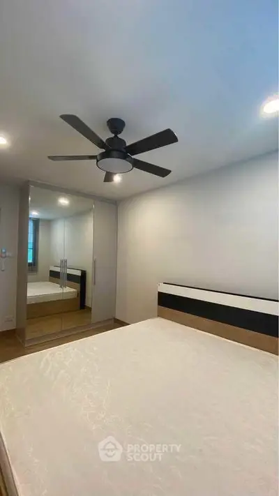 Modern bedroom with ceiling fan and mirrored wardrobe