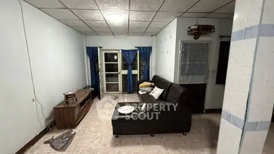 Cozy living room with black leather sofa and blue curtains, perfect for relaxation.