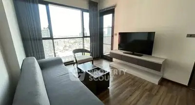 Modern living room with large windows and city view, featuring sleek furniture and wooden flooring.