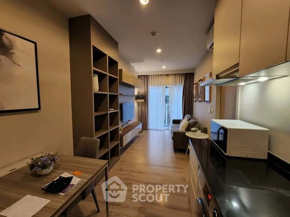 Modern living room with open kitchen, stylish shelving, and cozy dining area in a chic apartment.