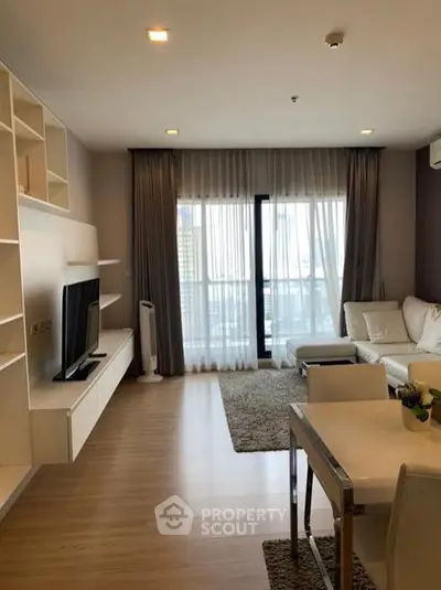 Modern living room with sleek furniture and large window offering natural light.