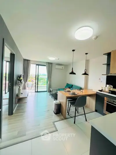 Modern open-layout kitchen and living room with balcony view in stylish apartment.