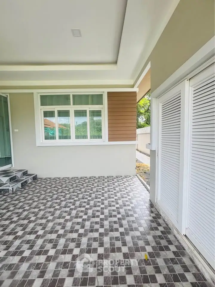 Charming exterior view of modern home with stylish tiled patio and elegant window design.