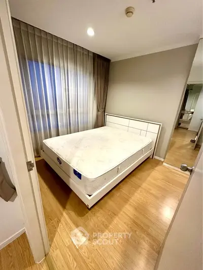 Spacious bedroom with elegant wooden flooring and large window for natural light.