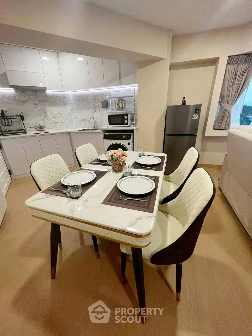 Modern kitchen with dining area, featuring sleek white cabinets and elegant dining table.