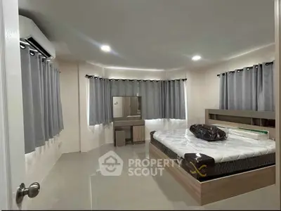Spacious bedroom with modern furnishings and ample natural light, featuring sleek tile flooring and elegant curtains.