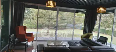Spacious living room with modern furniture and large glass windows overlooking a lush garden.