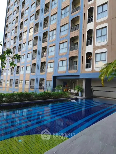 Modern apartment building with swimming pool and landscaped garden area.