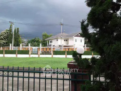 Charming suburban house with lush green lawn and stormy sky backdrop, perfect for serene living.