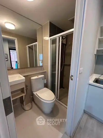 Modern bathroom with sleek fixtures and glass shower enclosure in contemporary apartment.