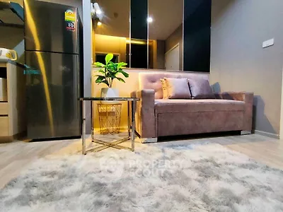 Modern living room with plush sofa, stylish rug, and sleek refrigerator in a cozy apartment setting.