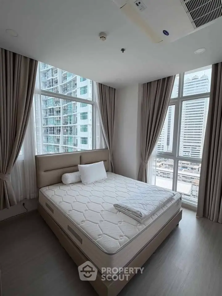 Modern bedroom with large windows offering stunning city views in a high-rise apartment.