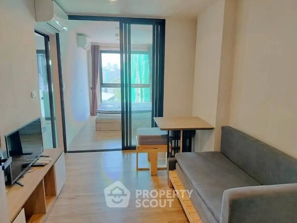 Modern apartment living room with cozy sofa and bedroom view