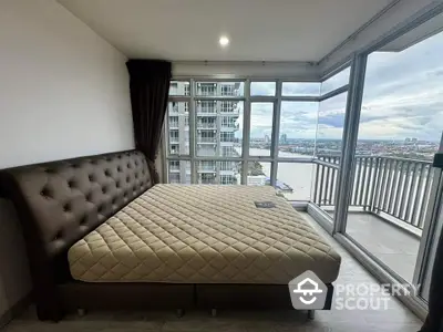 Spacious bedroom with stunning river view and large balcony access in modern high-rise apartment.