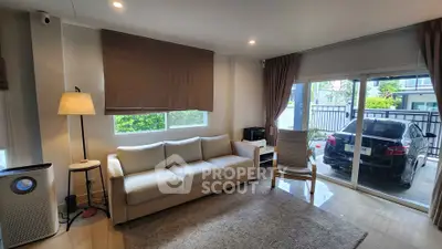 Modern living room with cozy sofa and large window overlooking a carport, perfect for family gatherings.