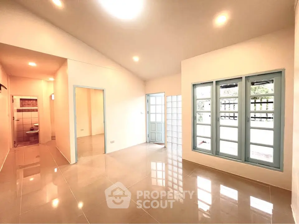 Spacious modern living room with glossy tile flooring and large windows for natural light.