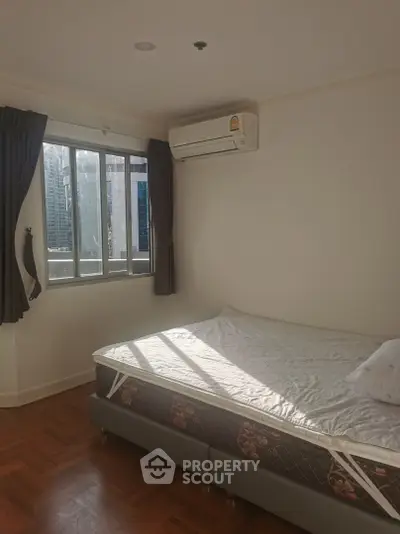 Bright bedroom with large window and air conditioning in modern apartment.