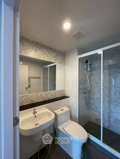 Modern bathroom with sleek design, featuring a glass shower and contemporary fixtures.