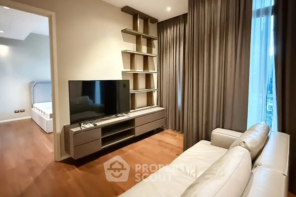 Modern living room with sleek TV unit and cozy sofa, adjacent to a stylish bedroom.