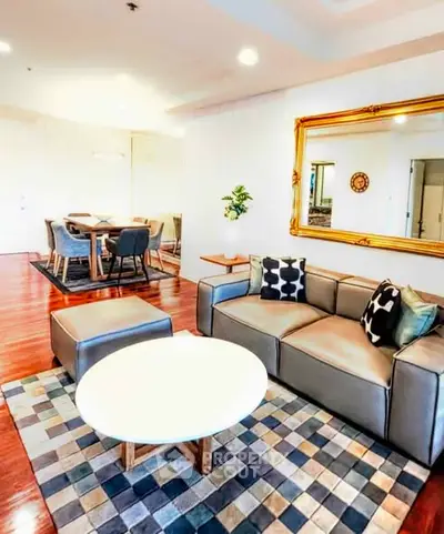 Spacious living room with modern decor and elegant dining area, featuring stylish furniture and a large mirror.