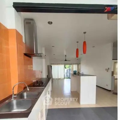 Spacious modern kitchen with open layout and vibrant orange accents, perfect for culinary enthusiasts.