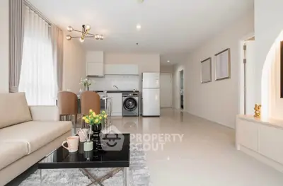 Modern open-plan living room with kitchen, featuring sleek furniture and bright natural lighting.
