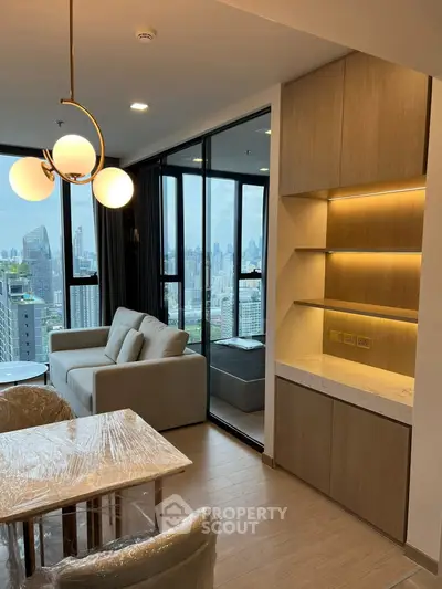Modern living room with city view, featuring elegant lighting and stylish furniture in a high-rise apartment.
