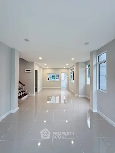 Spacious modern living room with glossy tiled floors and ample natural light.
