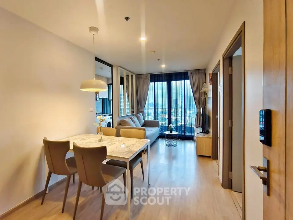 Modern living room with dining area and city view, featuring elegant decor and natural light.