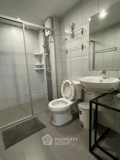 Modern bathroom with glass shower, sleek fixtures, and tiled walls in a contemporary home.