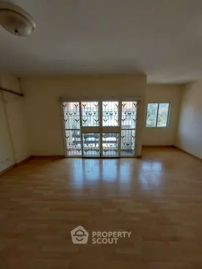Spacious empty room with large windows and wooden flooring, ideal for customization.