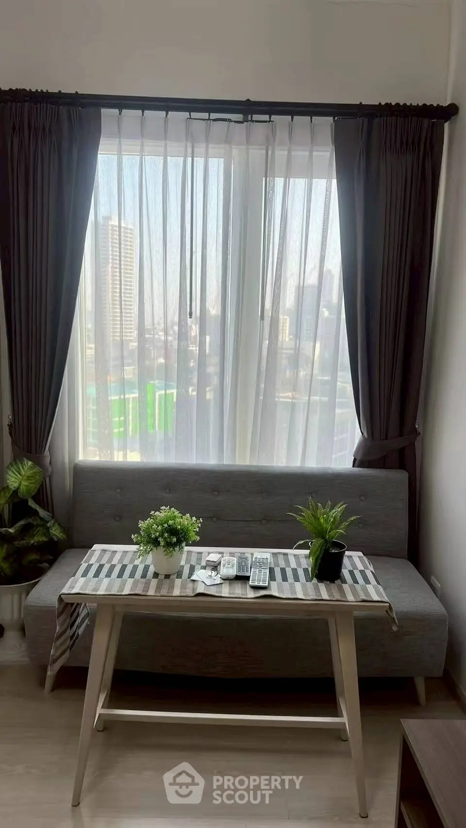 Chic living room with city view, modern sofa, and stylish decor in urban apartment.