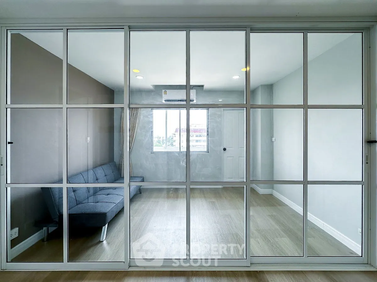 Modern living room with glass partition and sleek gray sofa