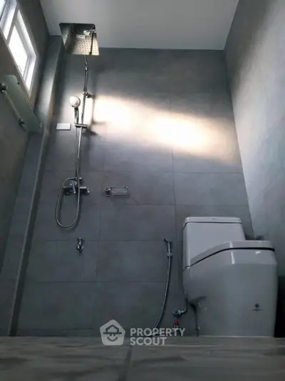 Modern bathroom with sleek gray tiles and a luxurious rainfall showerhead, offering a serene and stylish personal spa experience.