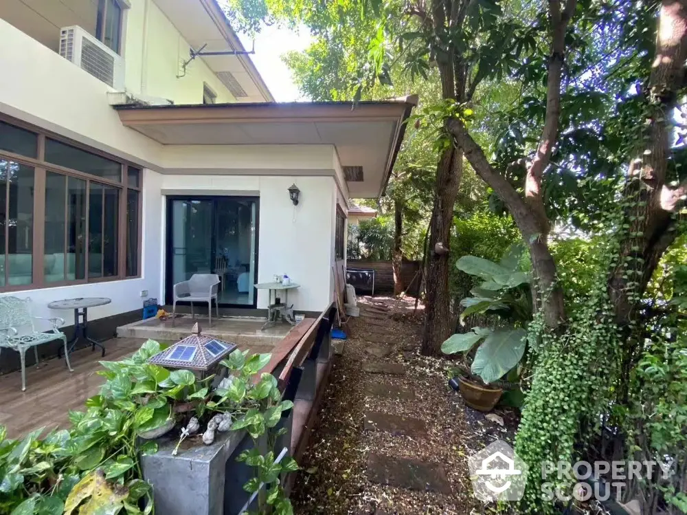 Charming garden view of a modern home with lush greenery and outdoor seating area.