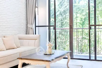 Bright living room with elegant sofa and coffee table, large windows with garden view.