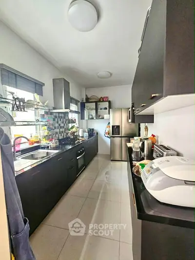 Modern kitchen with sleek black cabinets and stainless steel appliances, featuring a spacious countertop and stylish backsplash.