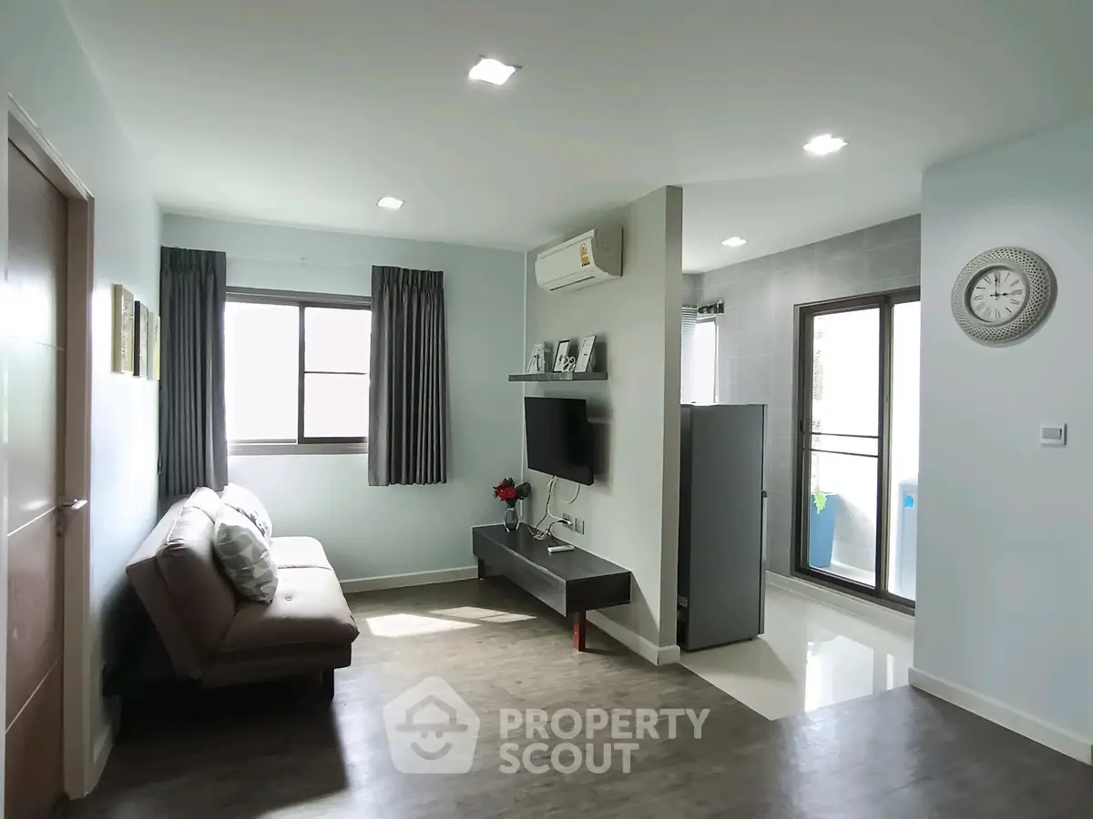 Modern living room with sleek design, featuring a wall-mounted TV, air conditioning, and a balcony view.