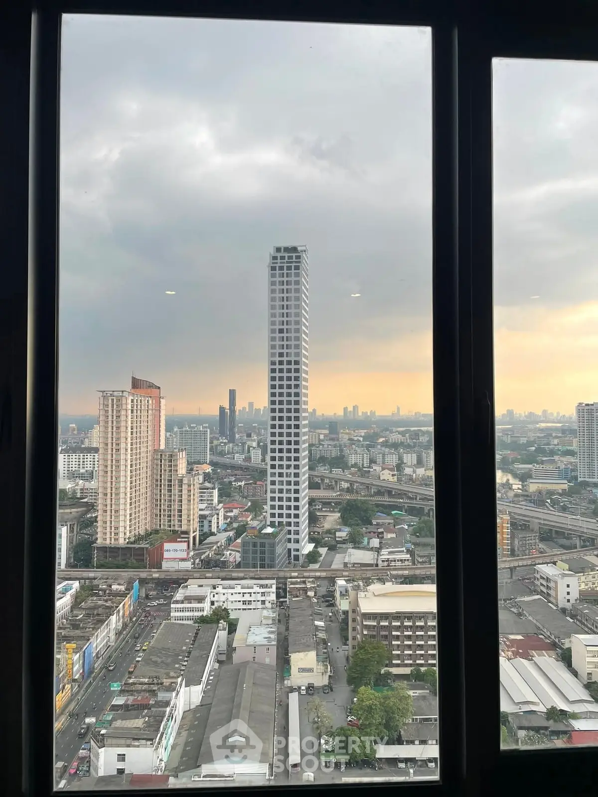 Stunning cityscape view from high-rise window showcasing urban skyline at sunset.
