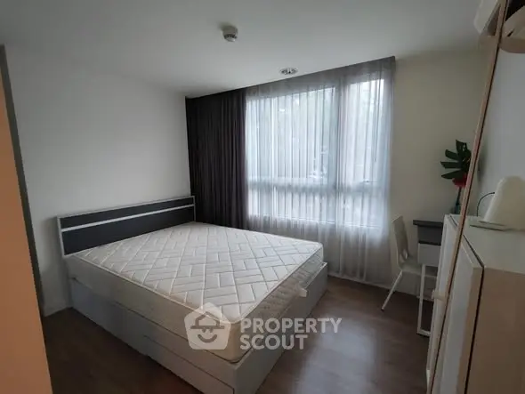 Cozy bedroom with large window and minimalist decor, perfect for relaxation.